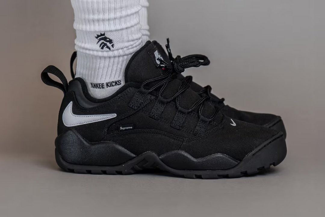 A glimpse of the Supreme x Nike SB Air Darwin Low "Black" worn on feet.